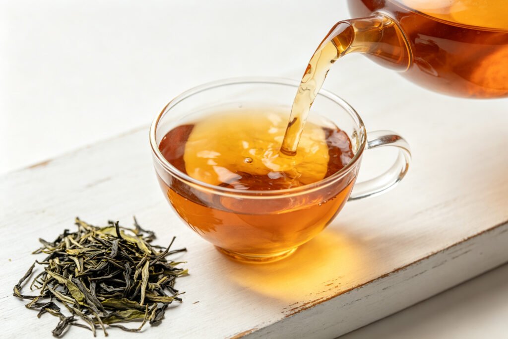 Pouring reddish Liubao tea into a glass cup with dry leaves beside it